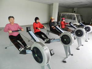 체험객들이.실내조정체험기구 에르고미터를 타고 있다. 